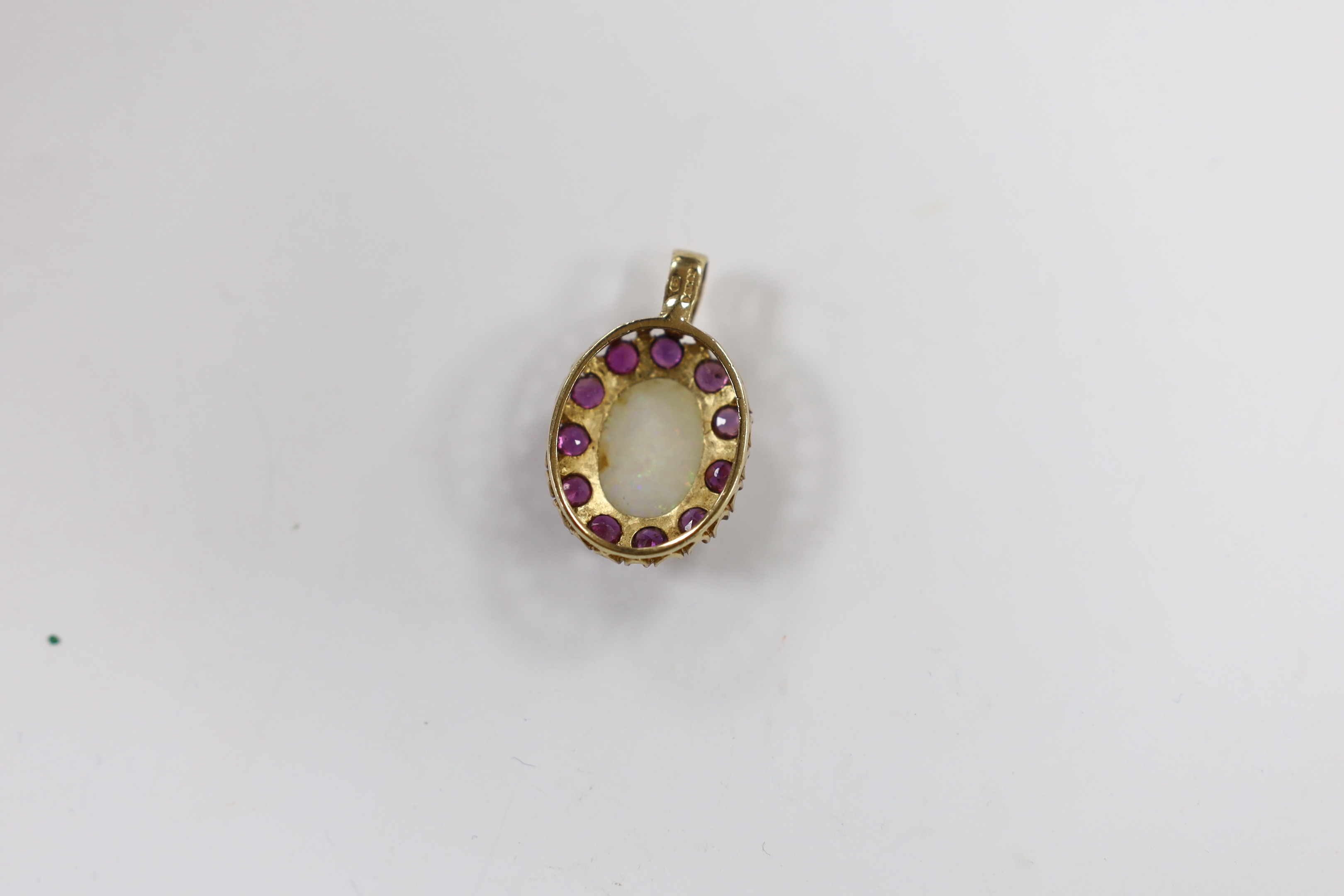 A modern 9ct gold, white opal and ruby set oval cluster pendant, overall 28mm, gross weight 3.6 grams.